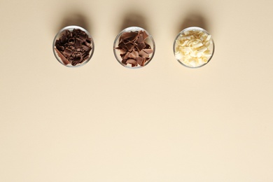 Bowls with different chocolate curls and space for text on color background, top view