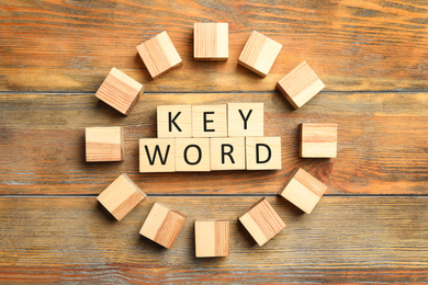 Cubes with word KEYWORD on wooden background, flat lay