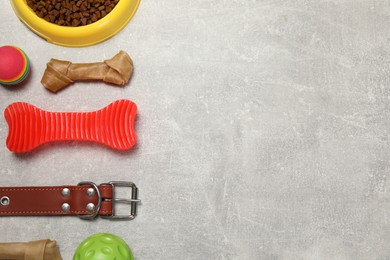 Photo of Flat lay composition with dog collar, toys and food on grey table. Space for text