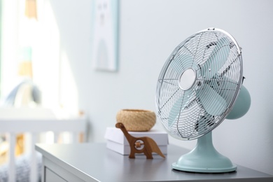 Photo of Modern fan on commode in baby room. Space for text