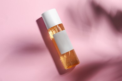 Photo of Bottle of cosmetic oil on pink background, top view