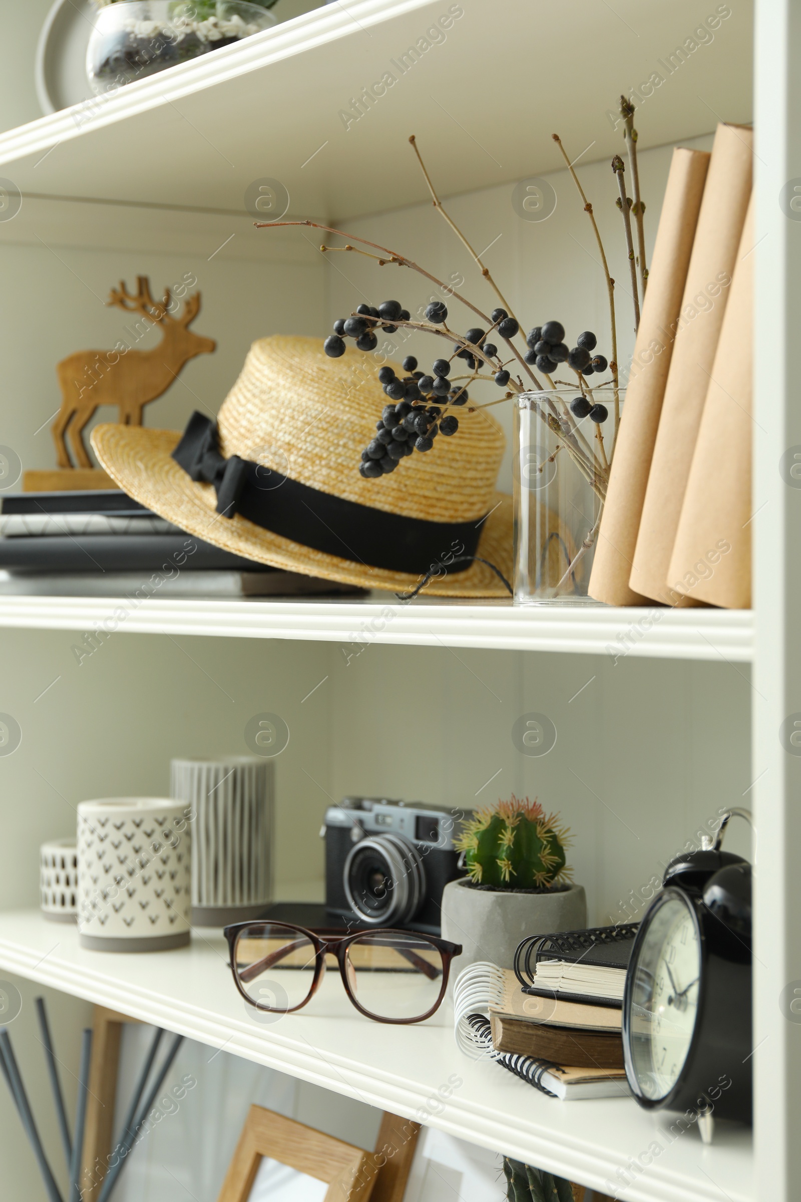 Photo of White shelving unit with straw hat and different decorative elements
