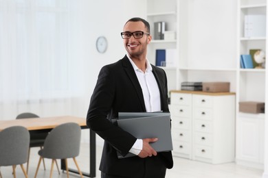 Photo of Smiling young businessman with folders in office