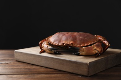 Photo of One delicious boiled crab on wooden table, space for text