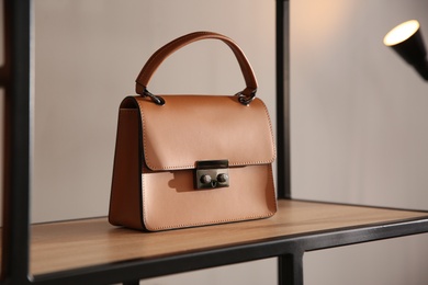 Photo of Elegant brown bag on shelf in luxury boutique