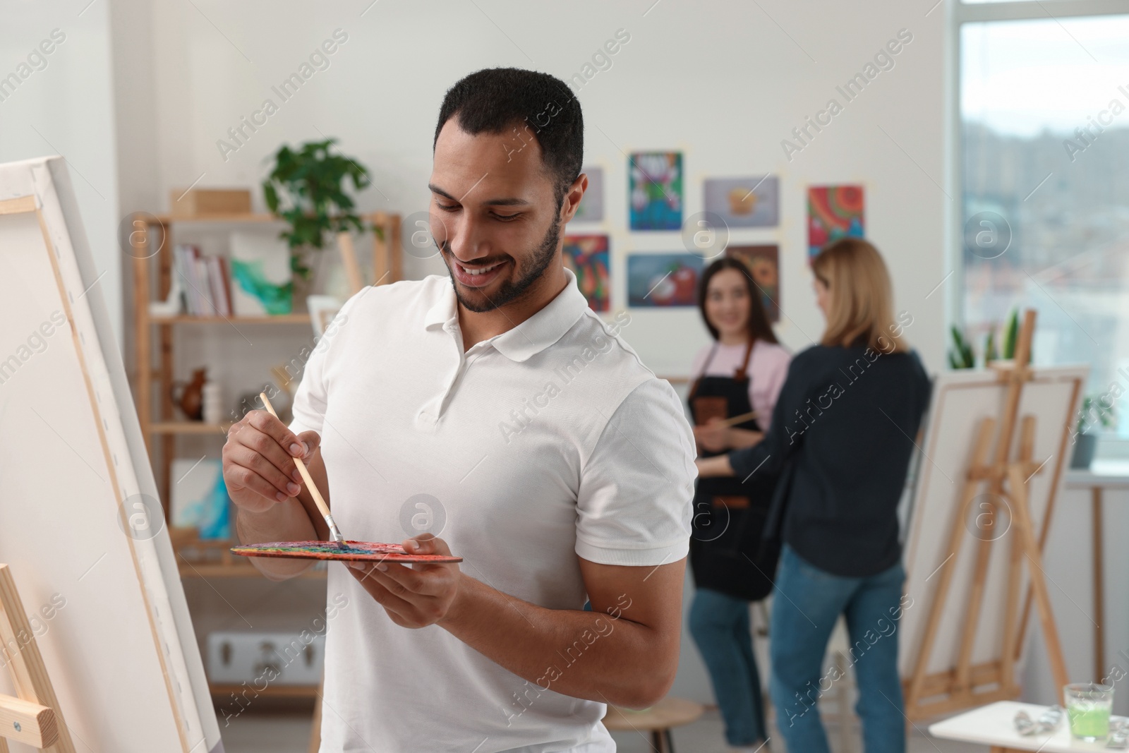 Photo of Group of students attending painting class in studio. Creative hobby