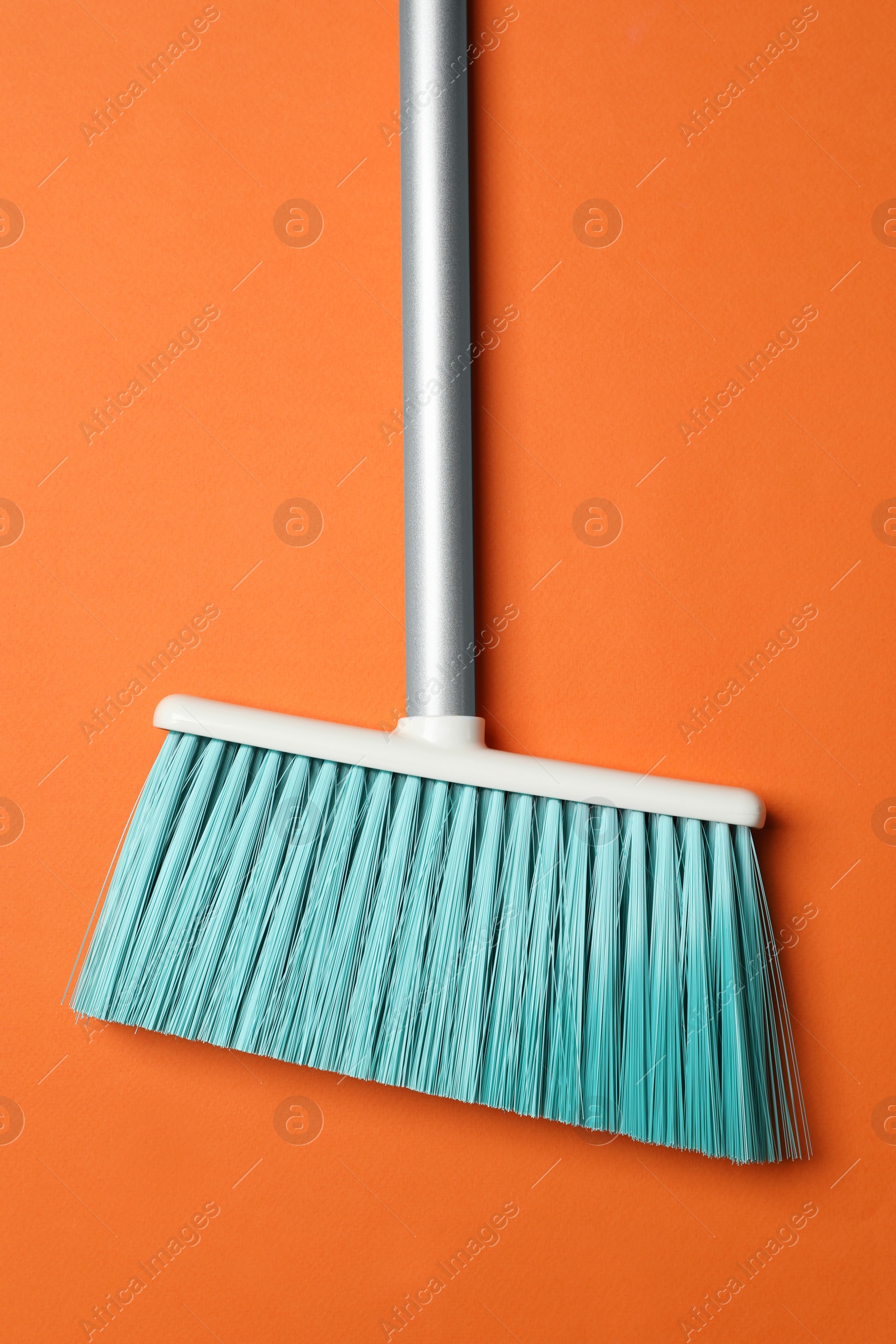 Photo of Plastic broom on orange background, top view