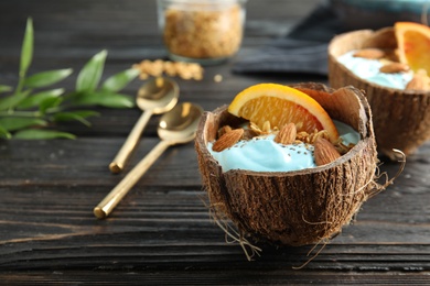 Photo of Coconut shell with spirulina smoothie on wooden table. Space for text