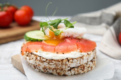 Photo of Crunchy buckwheat cakes with salmon, poached egg and cucumber slices served on board, closeup