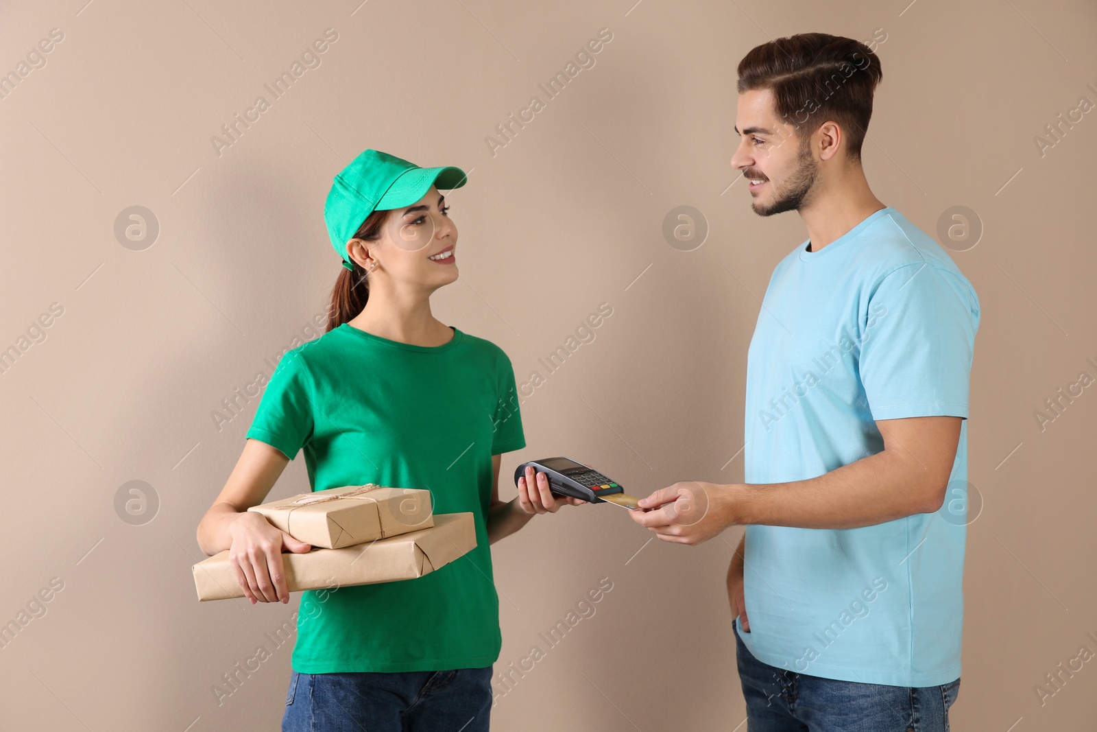 Photo of Young man with credit card using bank terminal for delivery payment on color background