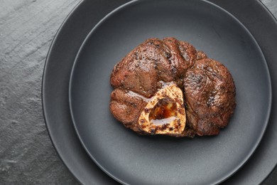 Photo of Piece of tasty grilled beef meat on black table, top view