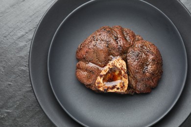 Piece of tasty grilled beef meat on black table, top view