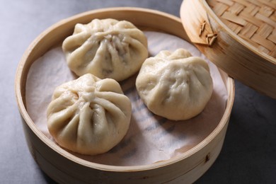 Photo of Delicious bao buns (baozi) on grey table, closeup