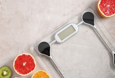 Photo of Bathroom scales, fruits and space for text on grey background, top view. Weight loss concept