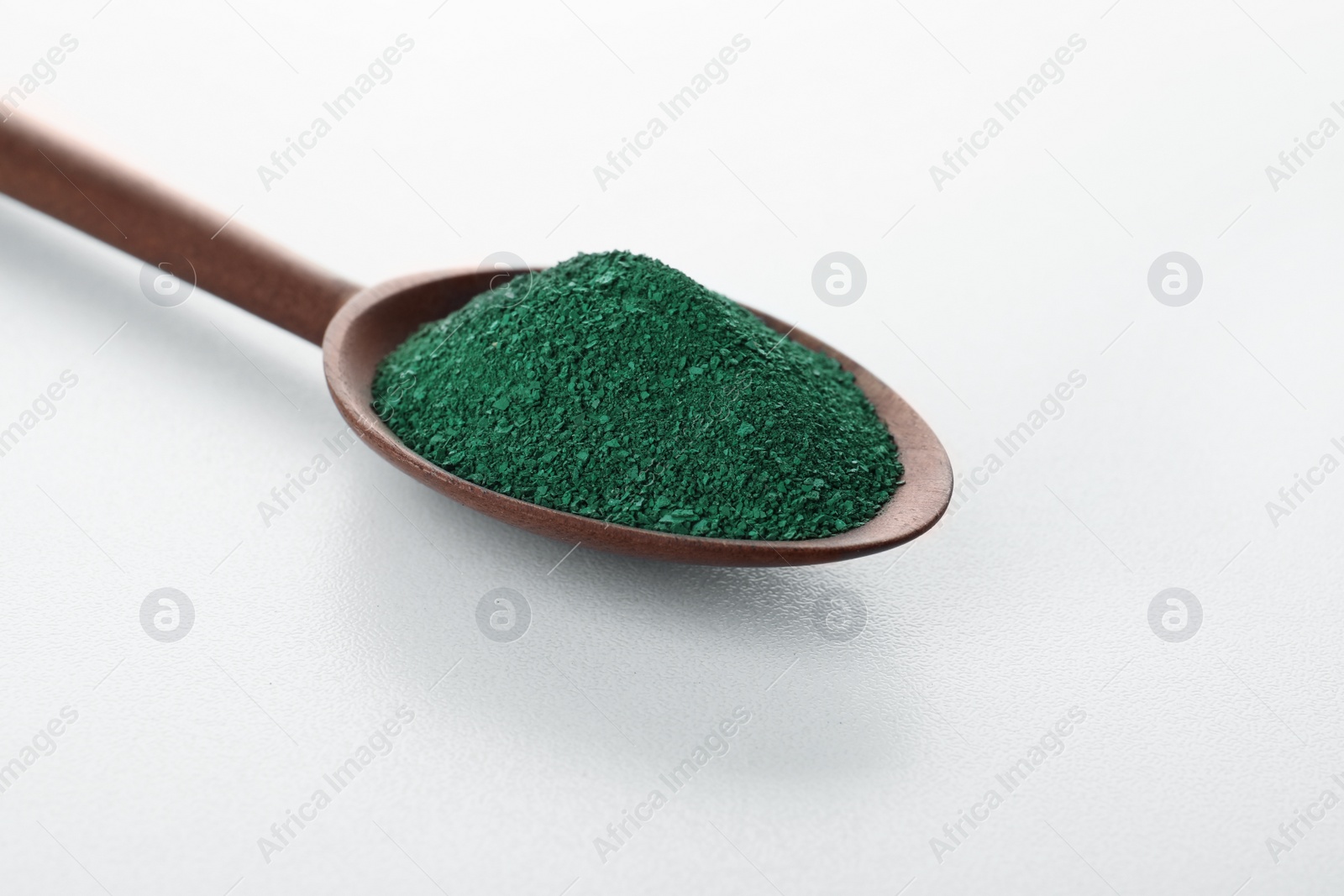 Photo of Spoon with spirulina algae powder on white background