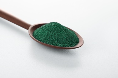 Spoon with spirulina algae powder on white background