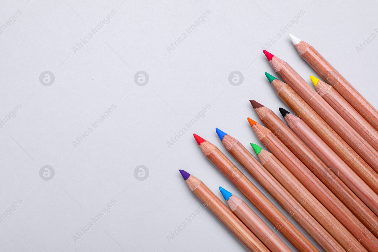 Photo of Colorful pastel pencils on white background, flat lay with space for text. Drawing supplies