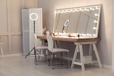 Modern mirror with light bulbs on dressing table in makeup room