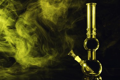 Photo of Glass bong and smoke on black background, space for text. Smoking device