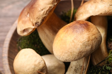 Photo of Fresh wild porcini mushrooms in wooden bowl, closeup
