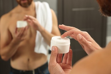 Photo of Man with jar of cream in bathroom, closeup