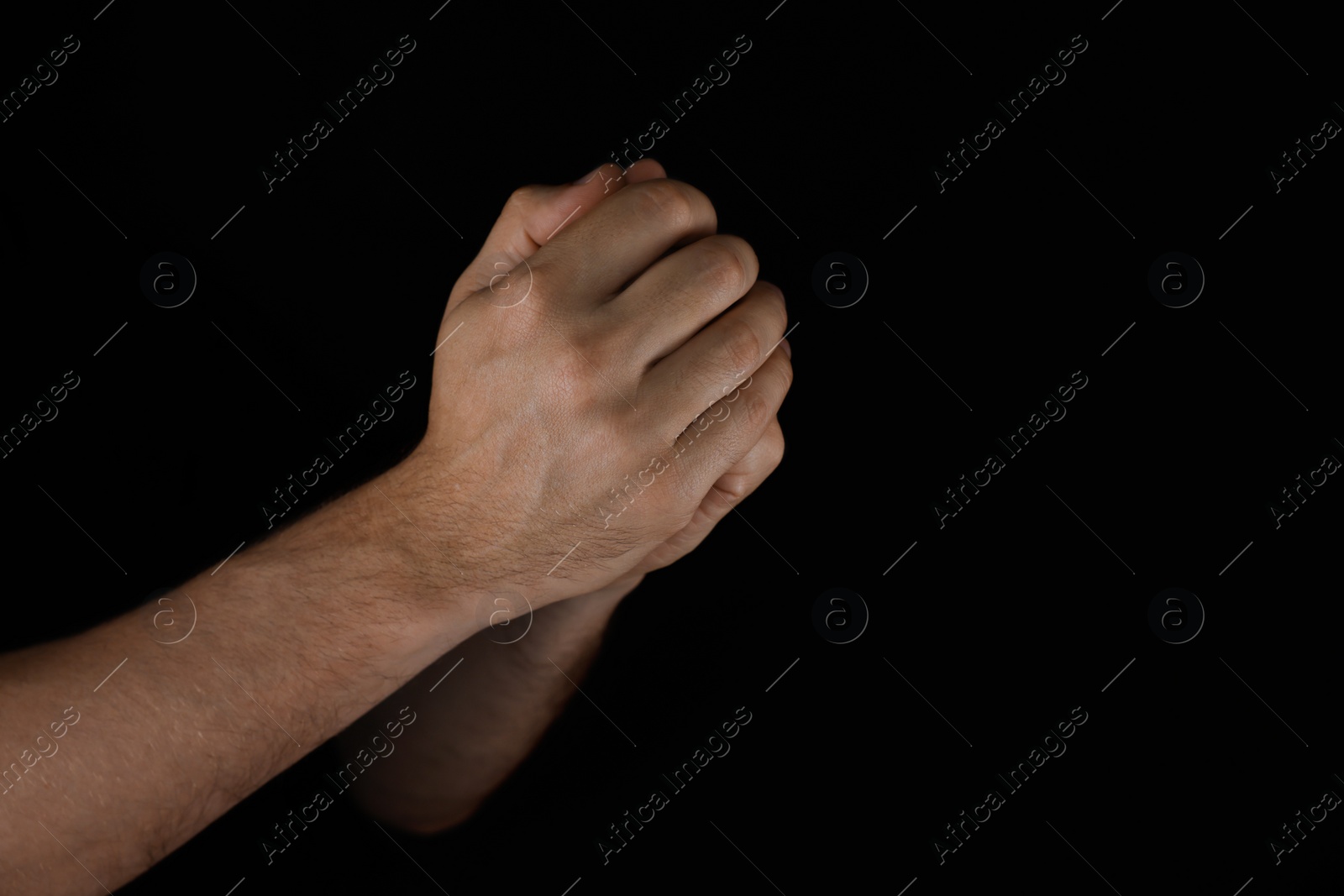 Photo of Man praying against black background, closeup view