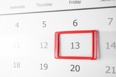 Closeup view of calendar page, focus on Friday 13. Bad luck superstition
