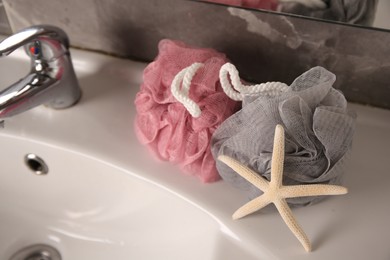 Photo of Colorful shower puffs and starfish on sink in bathroom