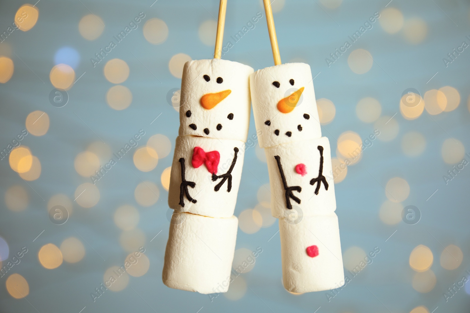 Photo of Funny snowmen made of marshmallows against blurred lights, closeup