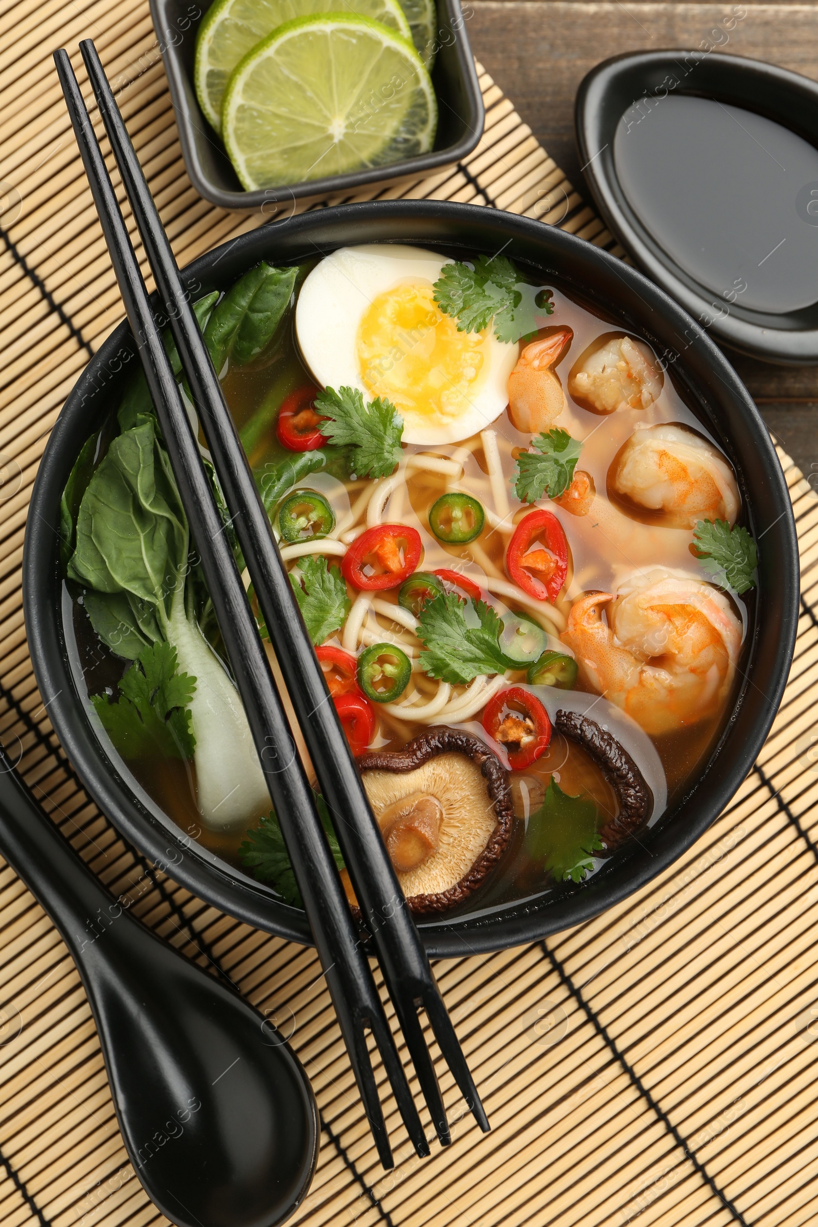 Photo of Delicious ramen with shrimps and egg in bowl served on table, flat lay