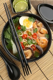 Delicious ramen with shrimps and egg in bowl served on table, flat lay