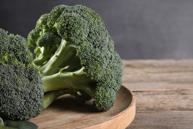 Photo of Fresh raw broccoli on wooden table, closeup and space for text