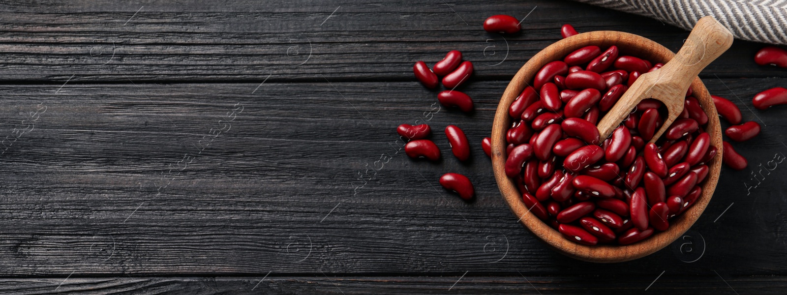 Image of Red kidney beans and space for text on dark wooden table, flat lay. Banner design