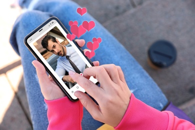 Woman visiting dating site via smartphone outdoors, closeup