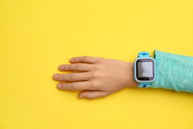 Photo of Boy with stylish smart watch on yellow background, top view