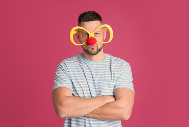 Emotional man with large glasses and clown nose on pink background. April fool's day