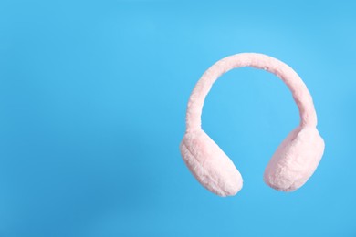 Photo of Stylish winter earmuffs on light blue background, space for text