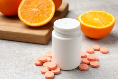 Photo of Dietary supplements. Plastic bottle, pills and oranges on grey table