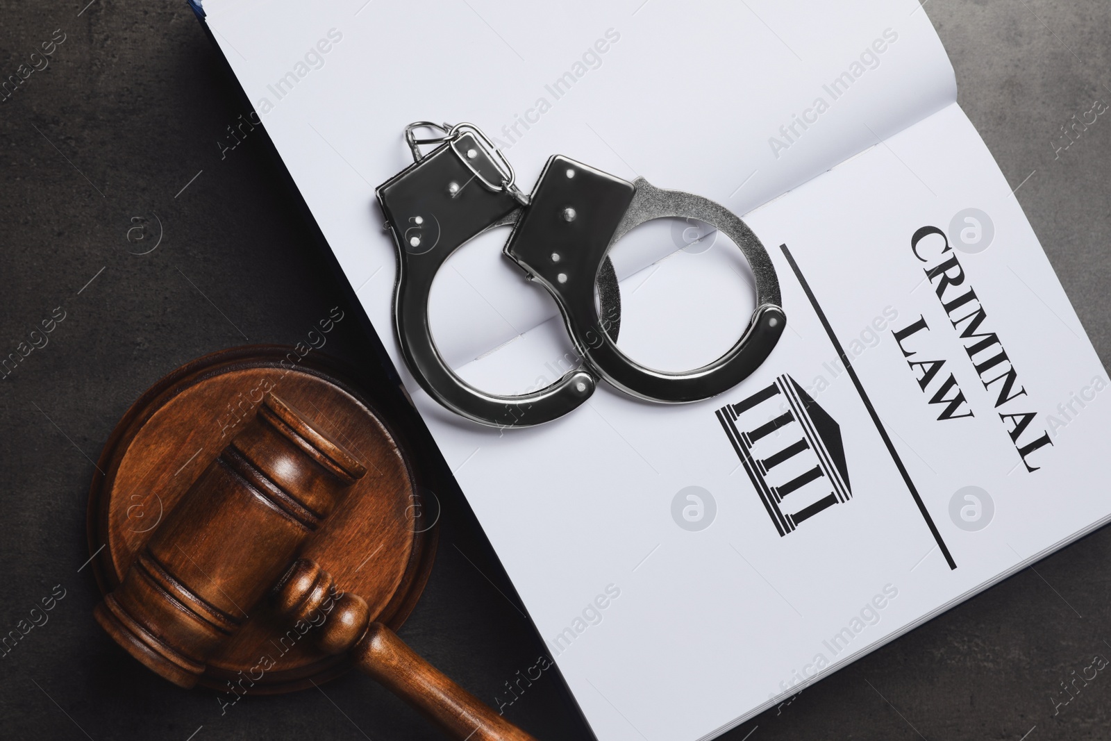 Photo of Judge's gavel, handcuffs and Criminal law book on grey background, flat lay