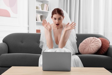 Surprised bride using laptop in living room