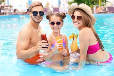 Photo of Happy family with cocktails in pool on sunny day