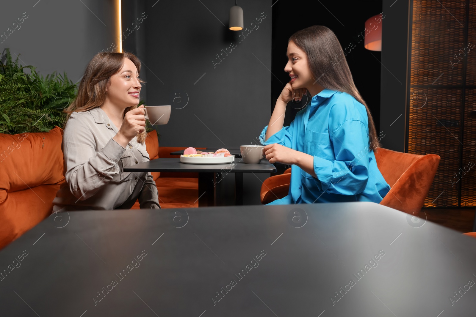 Photo of Young women with coffee spending time together in cafe