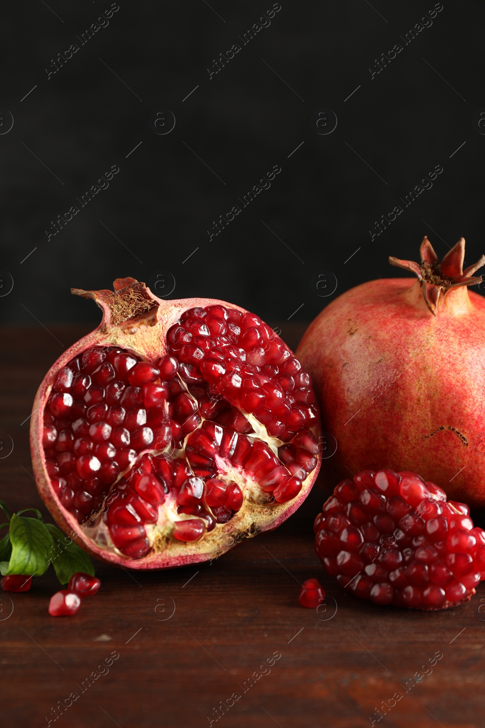 Photo of Fresh pomegranates and green leaves on wooden table