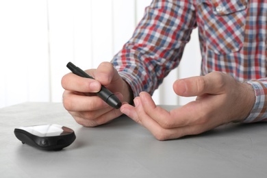 Man using lancet pen at table. Diabetes test