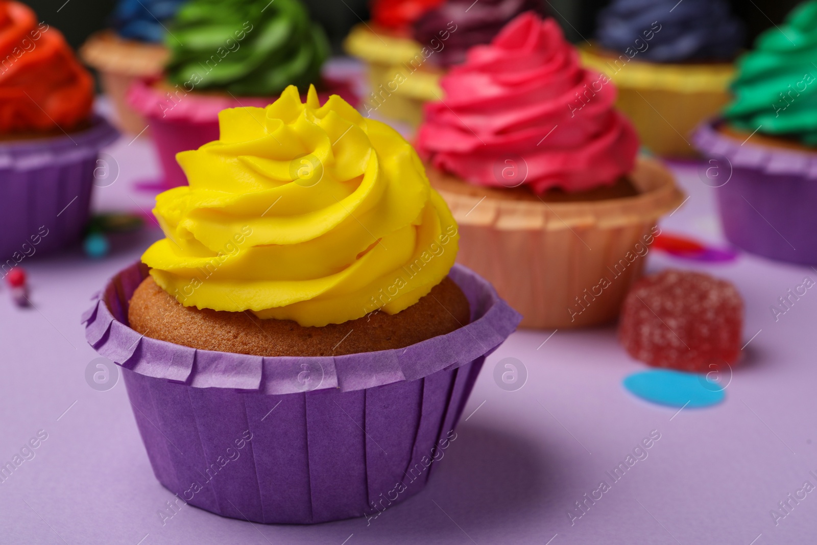 Photo of Delicious cupcake with yellow cream on violet table, space for text