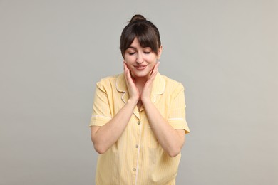 Photo of Happy woman in pyjama on grey background