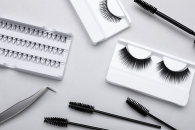 Photo of Flat lay composition with fake eyelashes, brushes and tweezers on light grey background