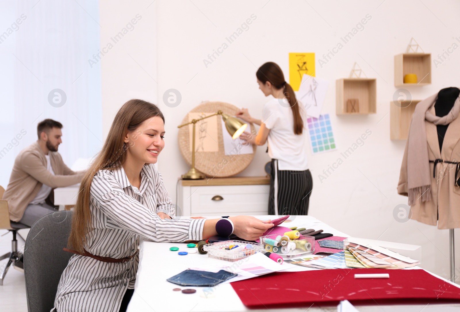 Photo of Fashion designer with colleagues creating new clothes in studio