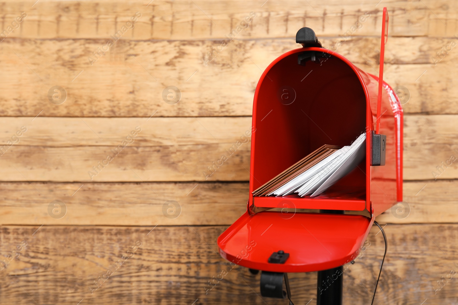 Photo of Open red letter box with envelopes against wooden background. Space for text