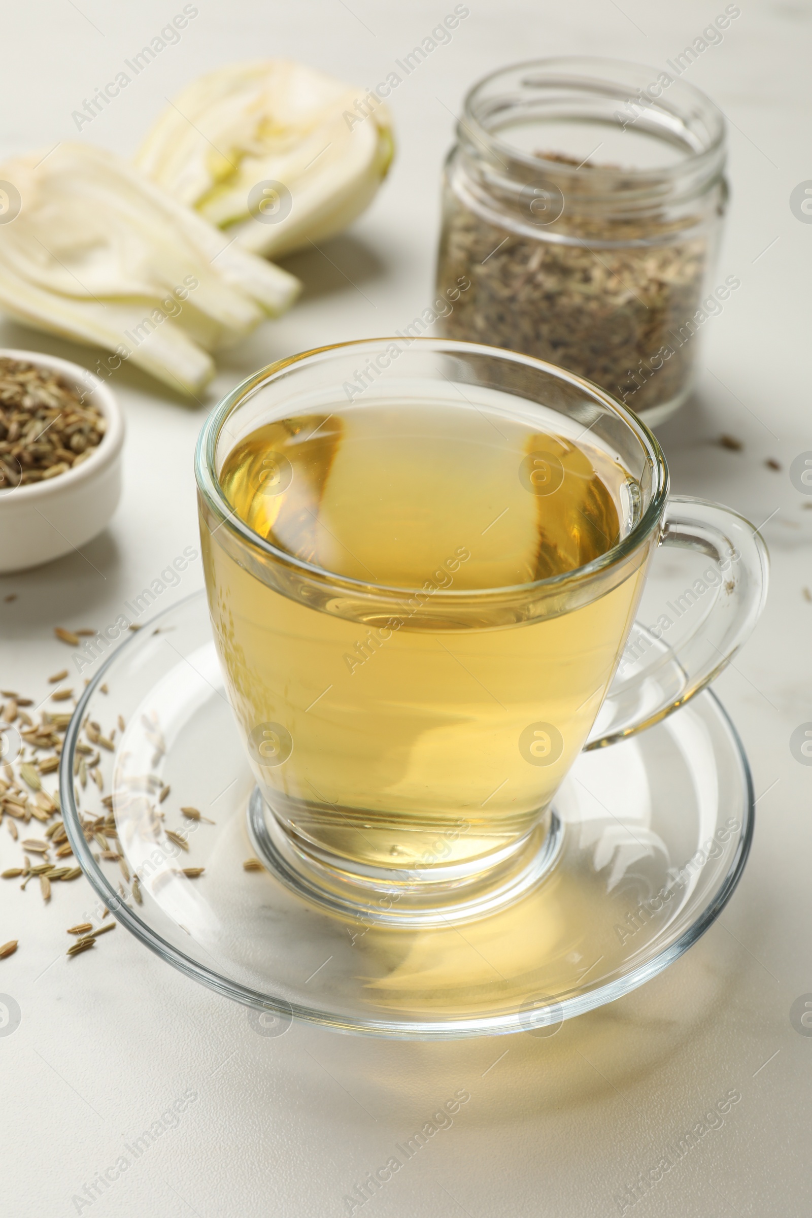 Photo of Aromatic fennel tea, seeds and fresh vegetable on white table, closeup